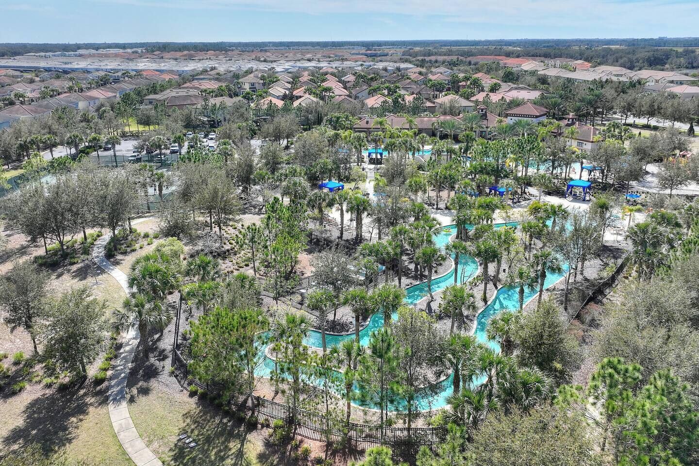 Quartiere residenziale con piscina circondata da alberi e cielo sereno.