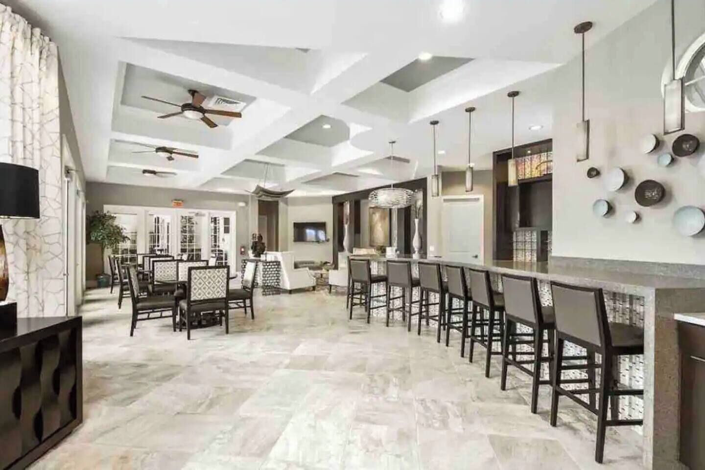 A spacious kitchen with a bar area, modern ceiling design, and a dining area with chairs and tables.