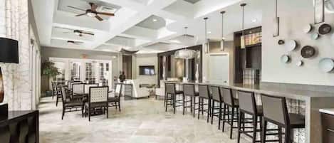 A spacious kitchen with a bar area, modern ceiling design, and a dining area with chairs and tables.