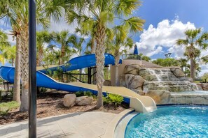A water park with a blue slide, a pool, and palm trees. - Solterra 5BD•Sleeps13•Private Pool•Disney•Resort (Davenport)