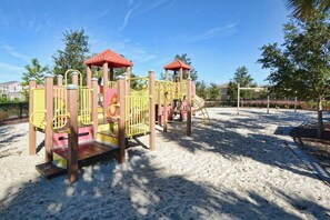A playground with a climbing structure, slides, and a fenced area. - Solterra 5BD•Sleeps13•Private Pool•Disney•Resort (Davenport)