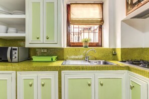 A kitchen with a green tiled backsplash, white cabinets, a stainless steel sink, and a gas stove. - Old Government Vacation Home (Roma)