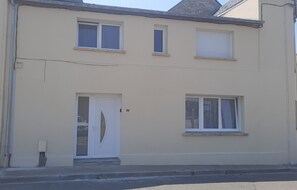 A two-story building with a flat facade, a central door, and three windows.