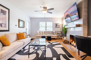 A modern living room with a sofa, coffee table, and a fireplace. - Parkway Palace: 5BR Pet friendly home near downtown Sleeps 10 Game Room included (Louisville)