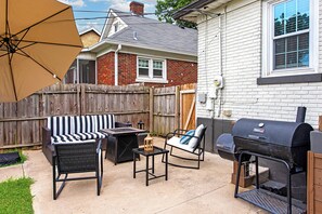 A backyard with a barbecue grill, outdoor furniture, and a wooden fence. - Parkway Palace: 5BR Pet friendly home near downtown Sleeps 10 Game Room included (Louisville)