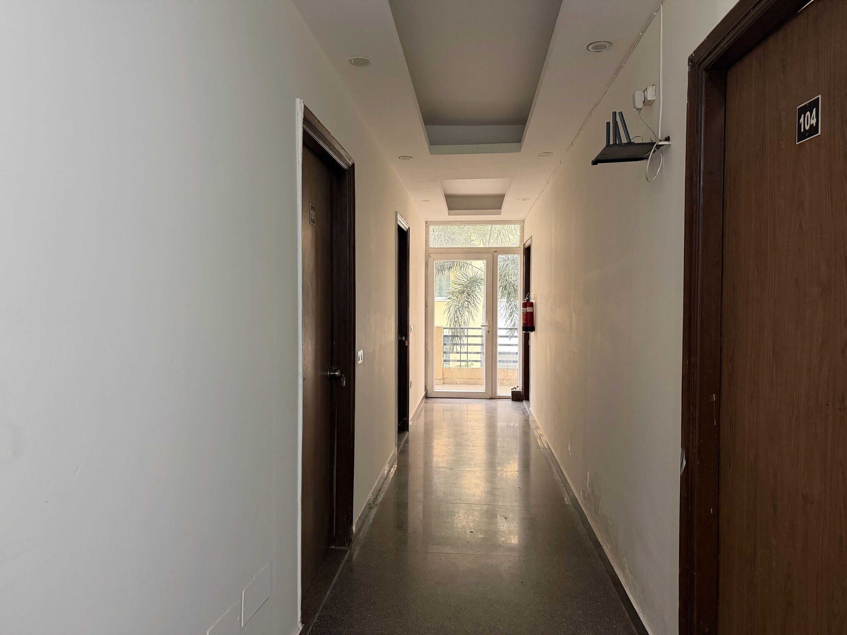 A corridor with doors on both sides, a fire extinguisher mounted on the wall, and a door with the number 104.