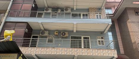 A multi-story building with balconies, air conditioning units, and a gated entrance.