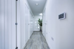 En gang med hvide døre, en plante og en lampe.