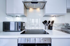 A modern kitchen with a microwave, oven, and stainless steel appliances. - Northfleet Luxe Panoramic Penthouse | River Thames View (Northfleet)