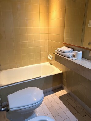 A bathroom with a bathtub, toilet, and a towel rack with towels. - Tango Apart en Avenida Corrientes (Buenos Aires)