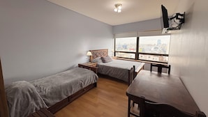 A room with two beds, a wooden desk, a chair, a lamp, and a TV mounted on the wall. - Tango Apart en Avenida Corrientes (Buenos Aires)