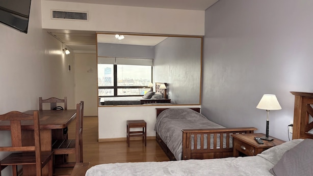A compact hotel room with a bed, a desk, and a chair. - Tango Apart en Avenida Corrientes (Buenos Aires)