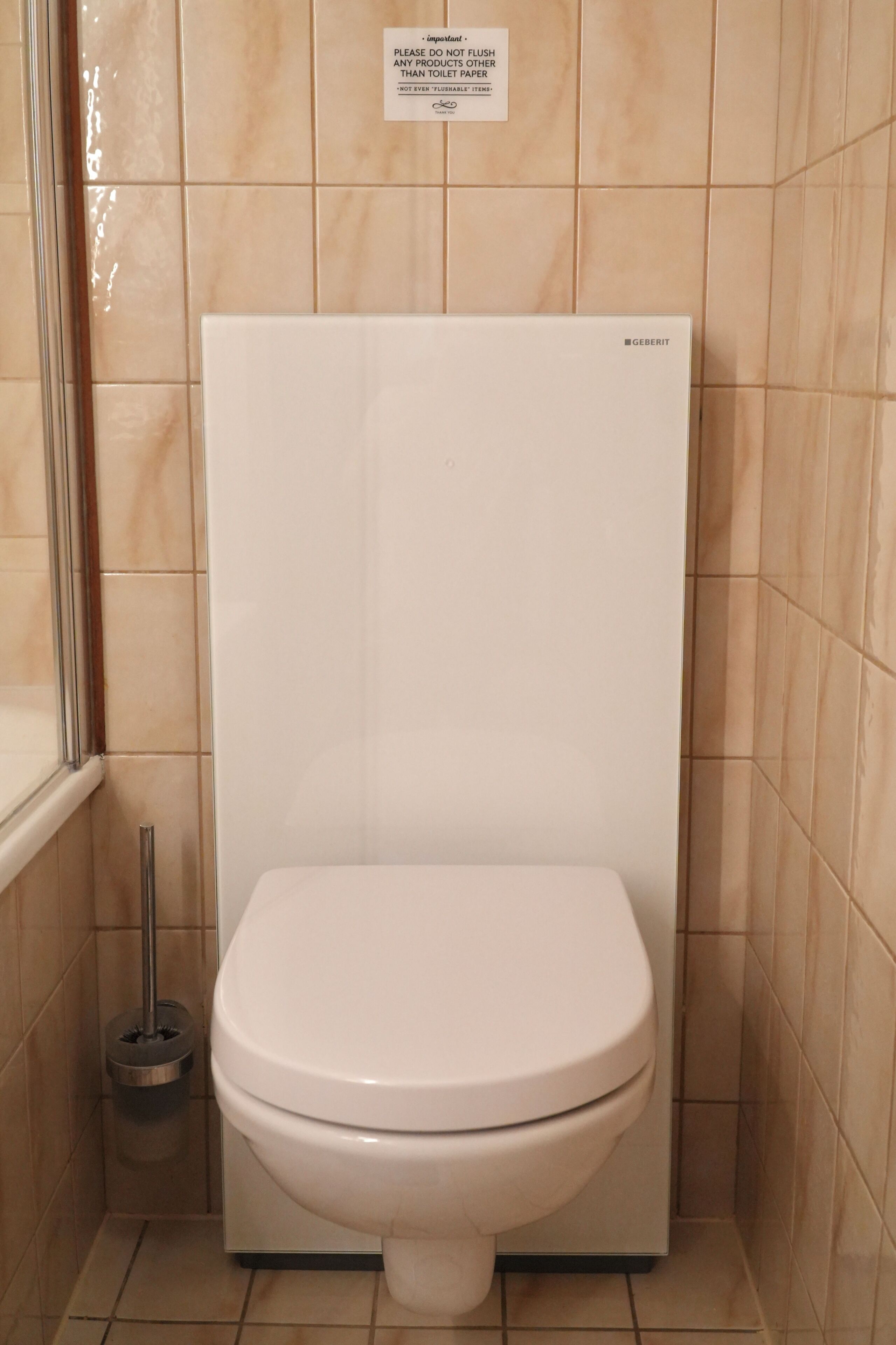A white toilet in a bathroom with beige tiles on the walls and floor.