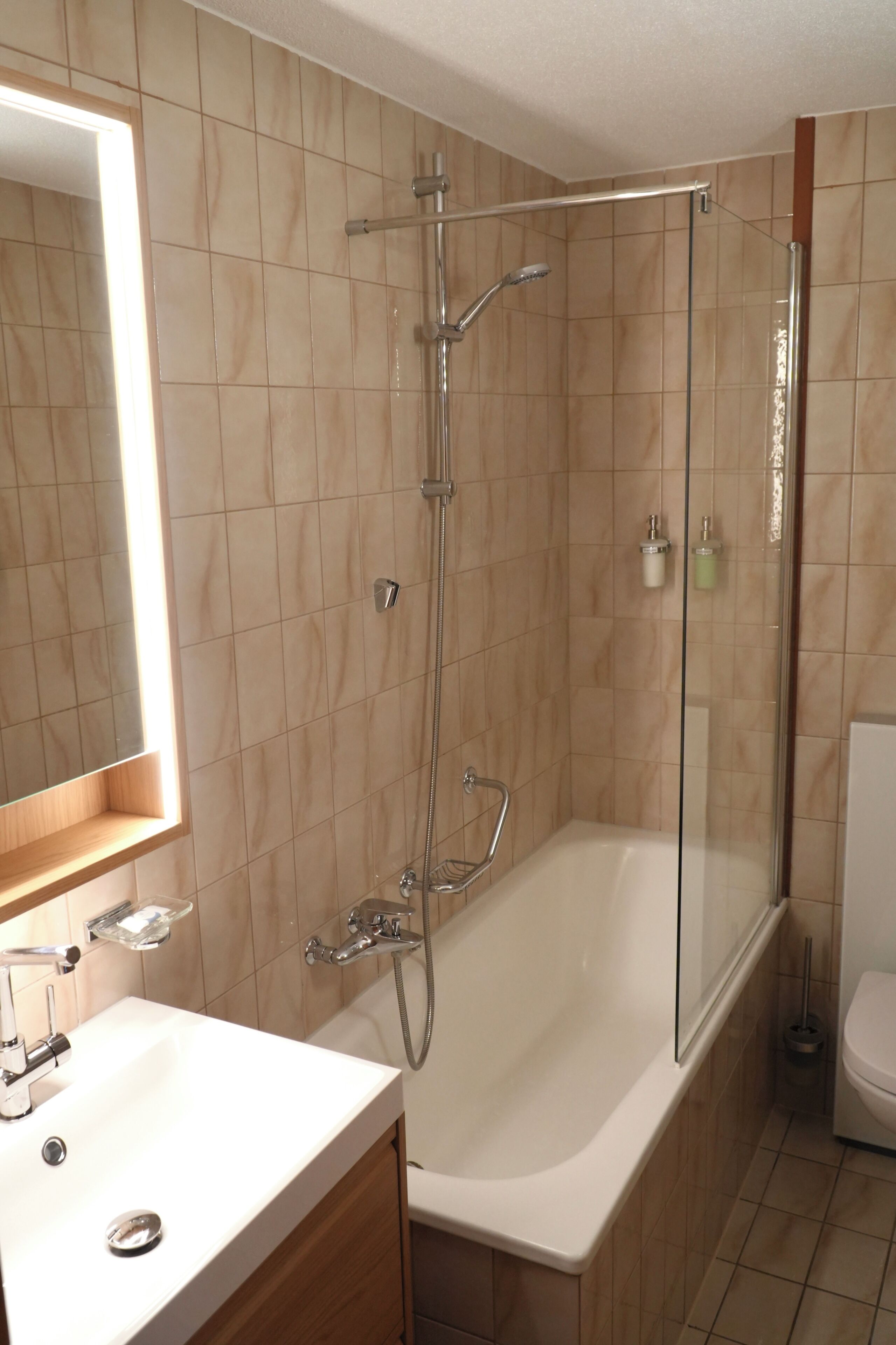 Une salle de bain avec une douche à parois de verre, une baignoire blanche et un miroir au-dessus du lavabo.