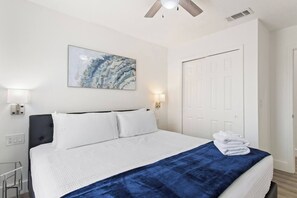 A hotel room with a bed, a ceiling fan, a painting, and a door. - Allure | Sleeps 8 | 3 BDM | Disney (Kissimmee)