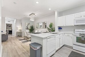 A modern kitchen with white cabinetry, a central island, and a built-in oven. - Royale Blue | 3 BDM | Sleeps 8 | Disney | Resort (Davenport)