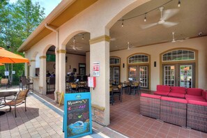 An outdoor patio area with tables and chairs, a red sofa, and a chalkboard sign advertising events. - Royale Blue | 3 BDM | Sleeps 8 | Disney | Resort (Davenport)