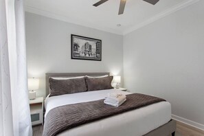 A hotel room with a bed, two bedside lamps, a framed picture on the wall, and a ceiling fan. - Royale Blue | 3 BDM | Sleeps 8 | Disney | Resort (Davenport)