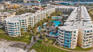 Resort com vários edifícios altos, piscina central e área de praia.