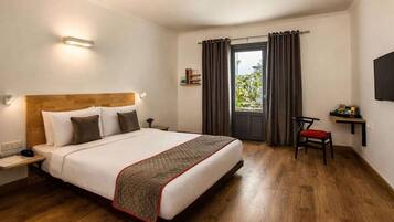A hotel room with a bed, bedside table, chair, and a TV on the wall.
