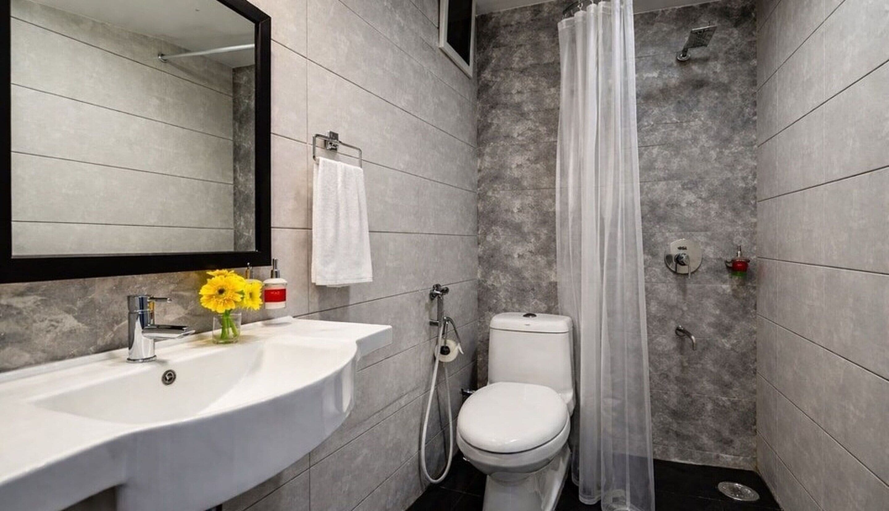 A modern bathroom with a white sink, toilet, and shower curtain.