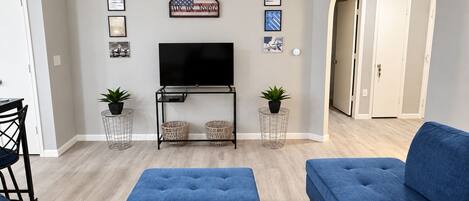 A living room with a TV, blue sofas, and a 'welcome' sign.