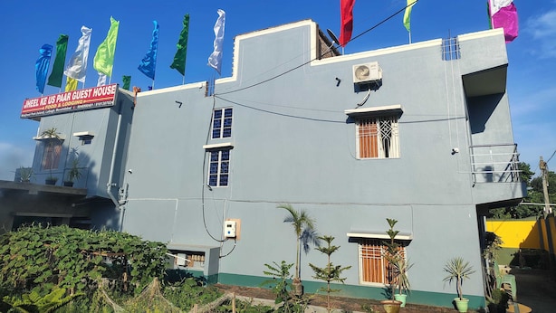 A building with multiple flags, a signboard, and a window with a barred design.