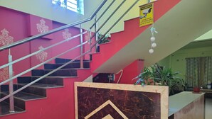 A staircase with a metal railing, a marble-patterned wall, and a warning sign about CCTV surveillance.