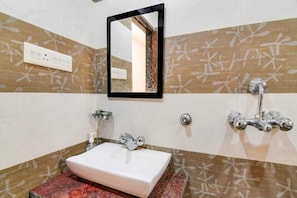 A bathroom with a white sink, a mirror, and a shower with a chrome faucet.