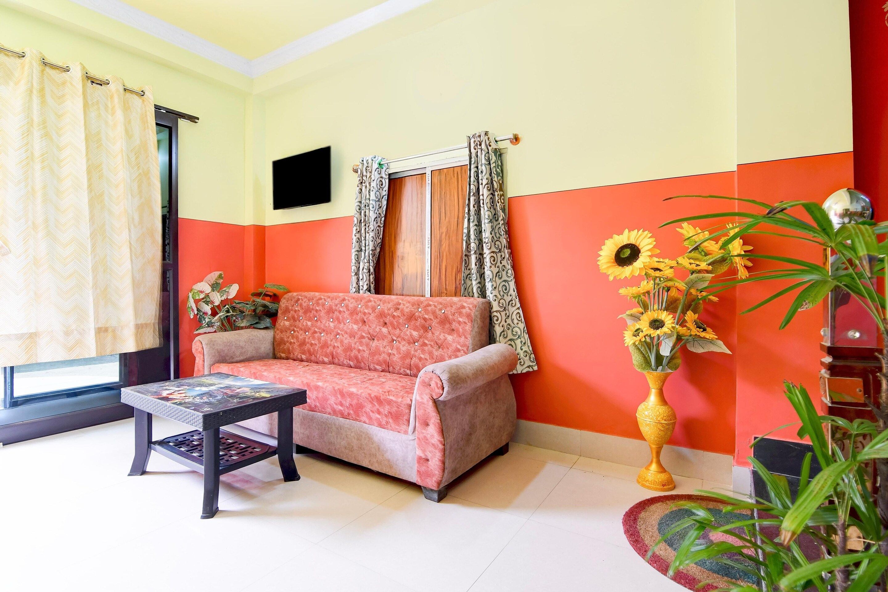 A living room with a sofa, a coffee table, a TV, and a vase with flowers.