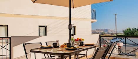 An outdoor dining area with a table, chairs, and a large umbrella.