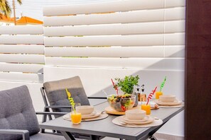Ein Essbereich mit einem Tisch für zwei Personen, ausgestattet mit einer Salatschüssel, einem Glas Orangensaft und einer Wasserflasche.