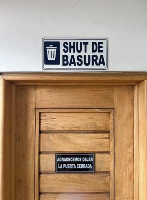 A wooden door with a sign above it that reads 'SHUT DE BASURA' and another sign below it that says 'AGRADECEOS DEJAR LA PUERTA CERRADA'. - Parque de la 93 Apartment - 404 (Bogota)