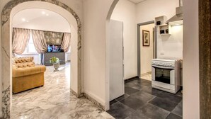 A hallway with a marble floor, a sofa, and a kitchen area with a stove. - CRISPI HOLIDAY IN (Roma)
