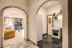 A hallway with a marble floor, a sofa, and a kitchen area with a stove. - CRISPI HOLIDAY IN (Roma)