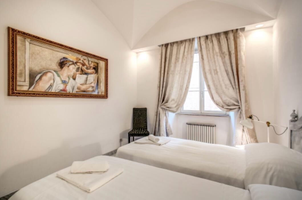 Ein Hotelzimmer mit zwei Betten, einem Heizkörper, einem Bild an der Wand und einem Fenster mit Vorhängen.
