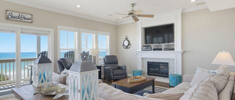 Un salon avec vue sur l’océan, une cheminée et un ventilateur de plafond.