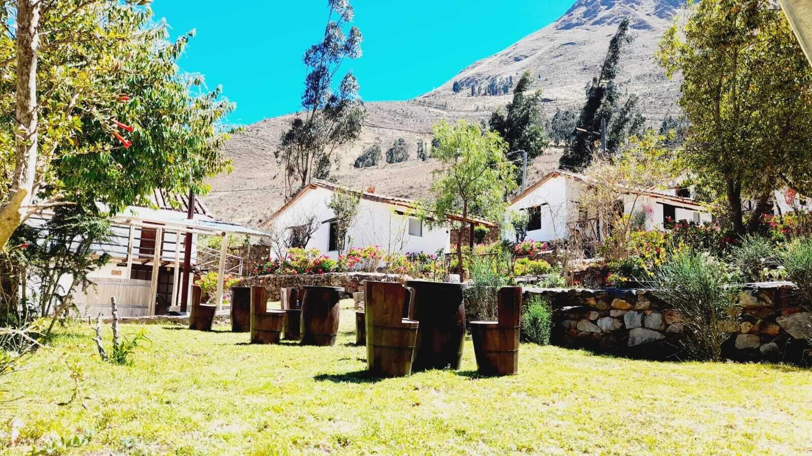 Entorno rural con muro de piedra, mobiliario de madera y montaña al fondo.
