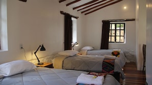 Quarto com duas camas, uma janela com vista e um abajur numa mesinha de cabeceira.