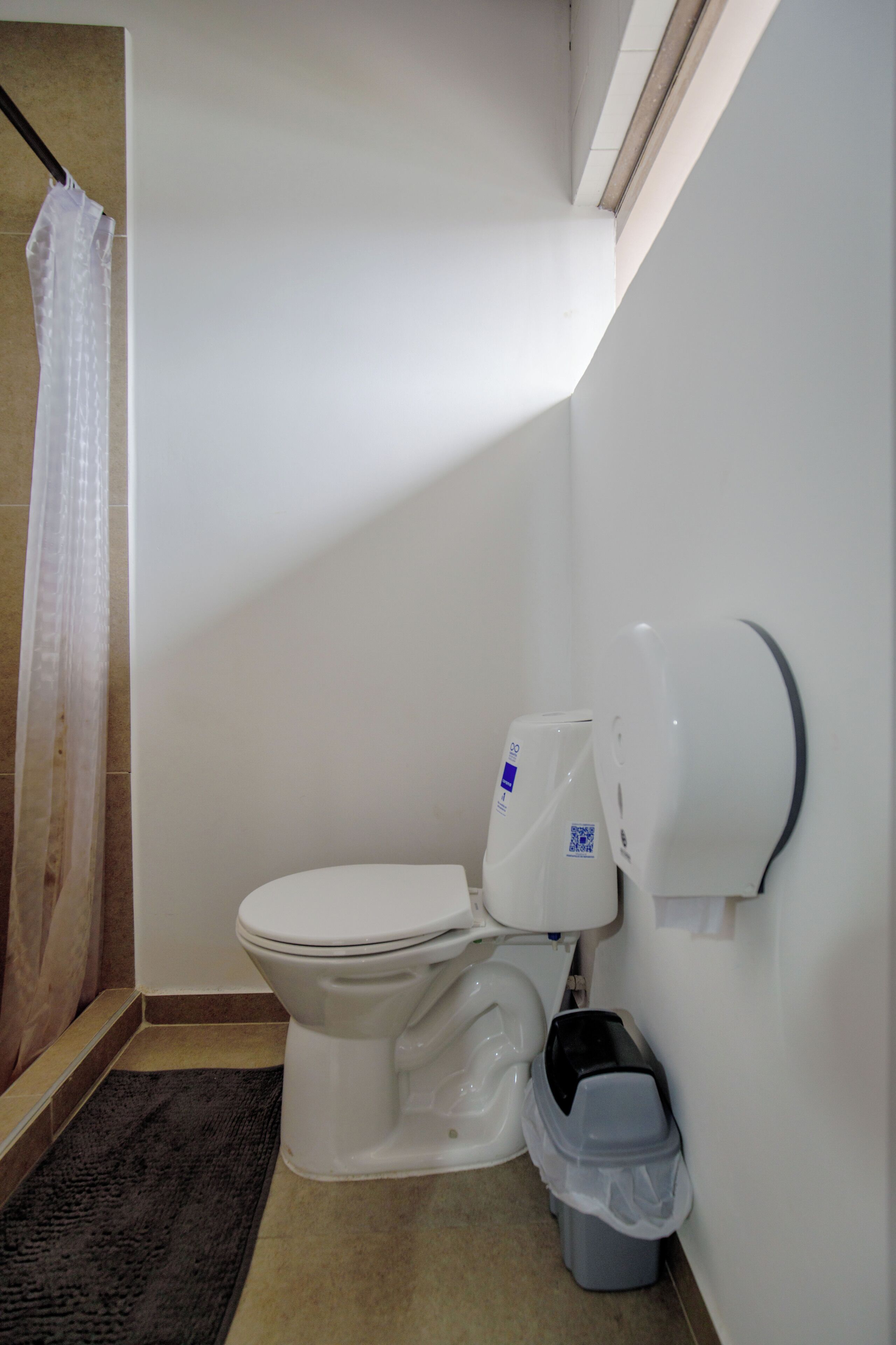 Een badkamer met een toilet, een prullenbak en een douchegordijn.
