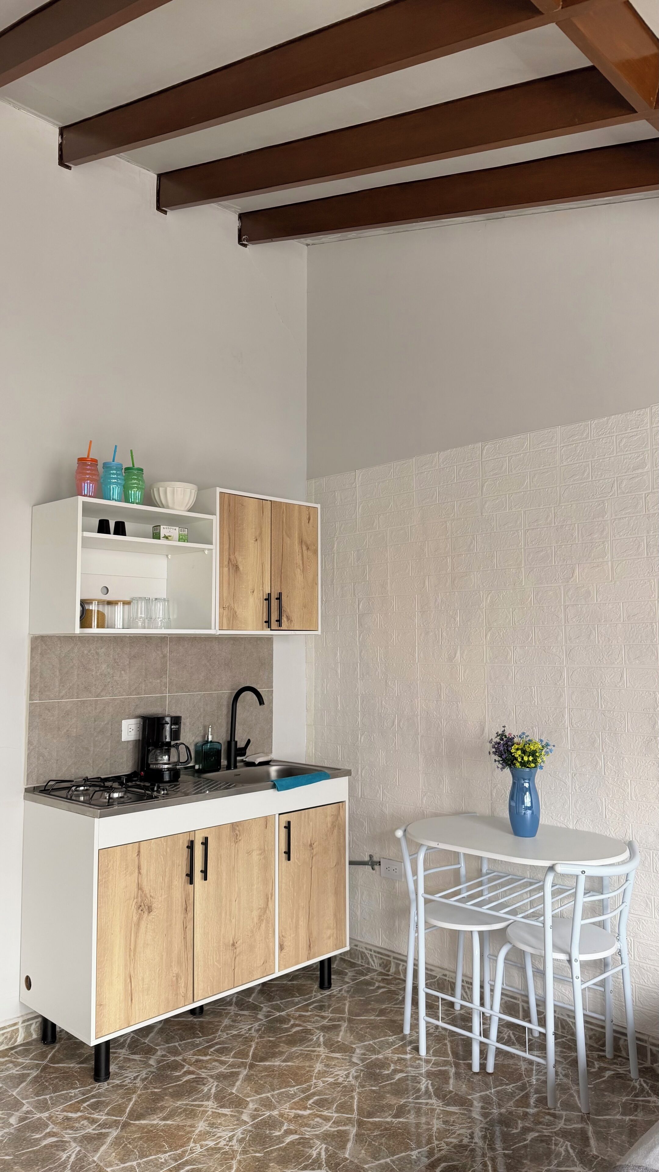 A compact kitchen with a gas stove, white cabinets, and a small dining table with a chair.