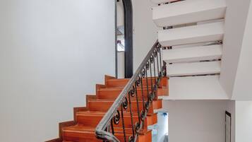 A staircase with wooden steps and a metal railing, leading to a landing with a white wall and a door.