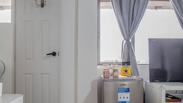 Una kitchenette equipada con refrigerador, cafetera y ventana con cortinas.