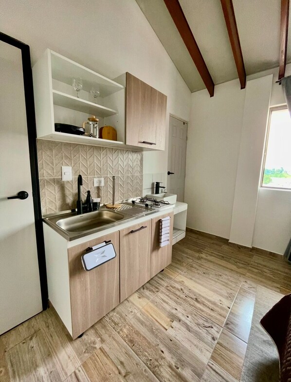 Een compacte keuken met een inbouwspoelbak, houten kastjes en een backsplash met een herringbone-patroon.