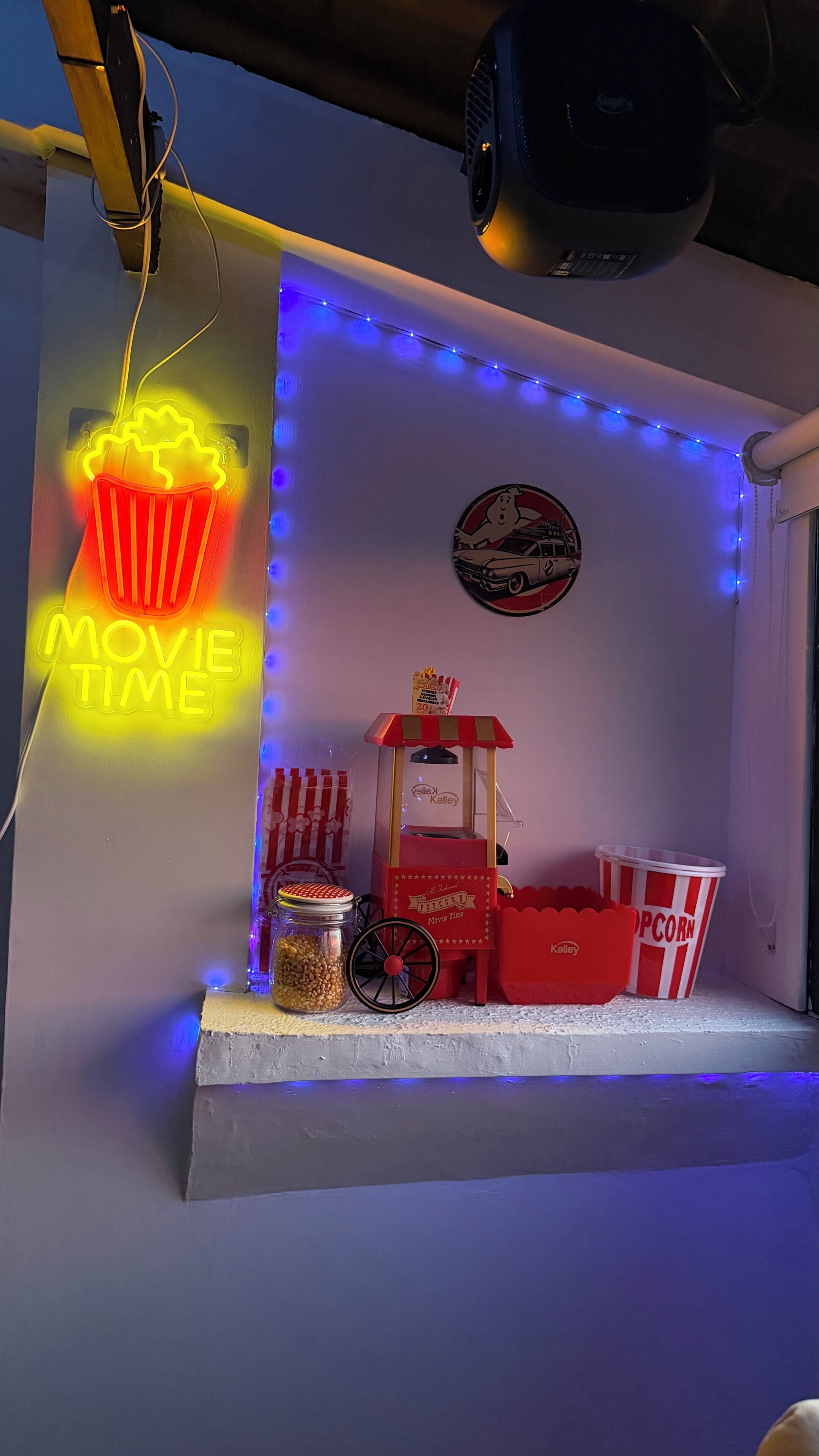 Een miniatuurchal voor een filmvoorstelling, met een neonbord, een popcornkraam en snacks.