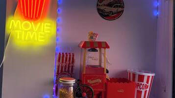 Een miniatuurchal voor een filmvoorstelling, met een neonbord, een popcornkraam en snacks.
