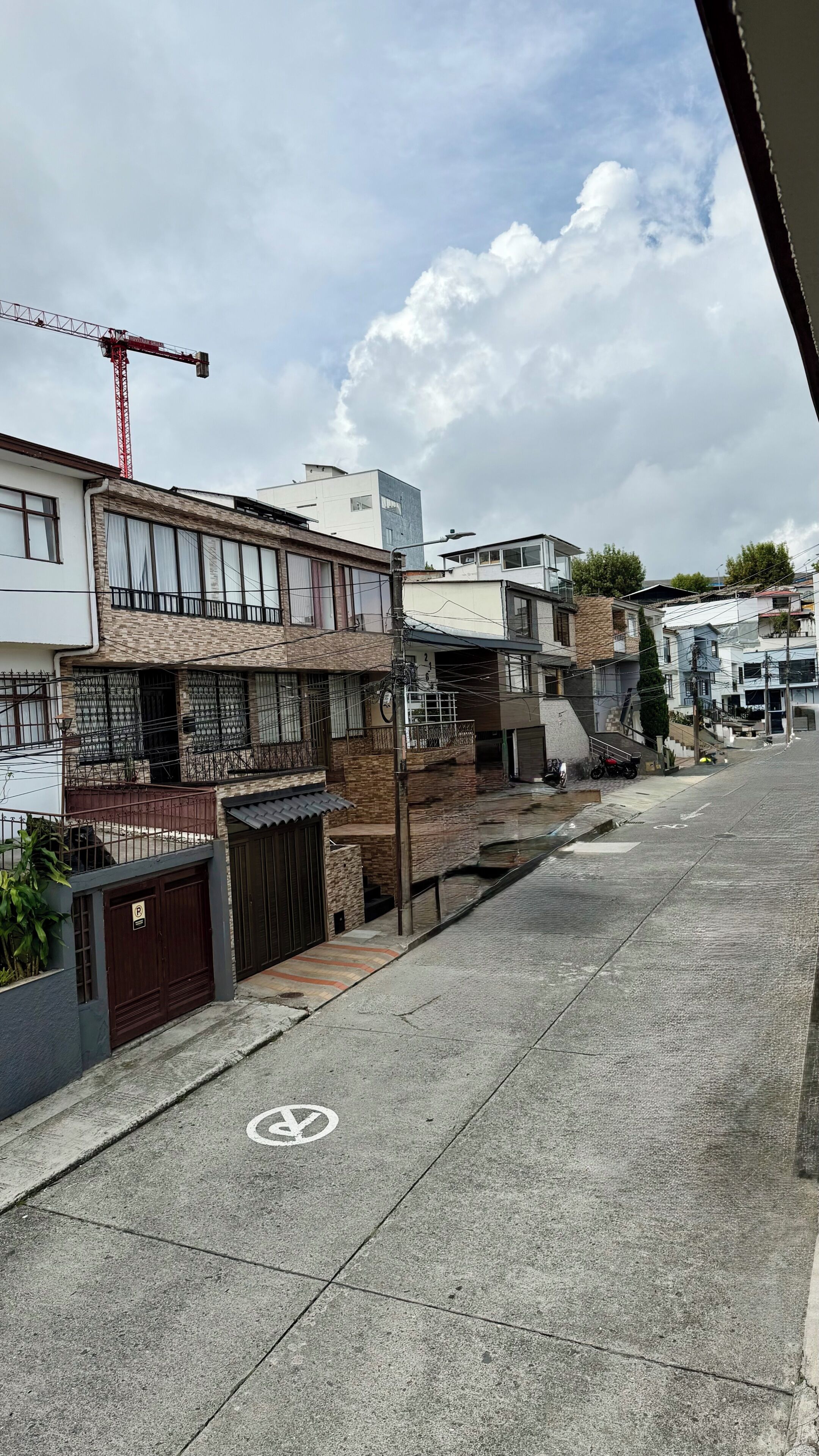 A residential street with houses, a construction crane, and a bicycle.