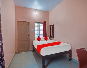 A bedroom with a single bed, a door, a window with curtains, and a wall-mounted mirror.