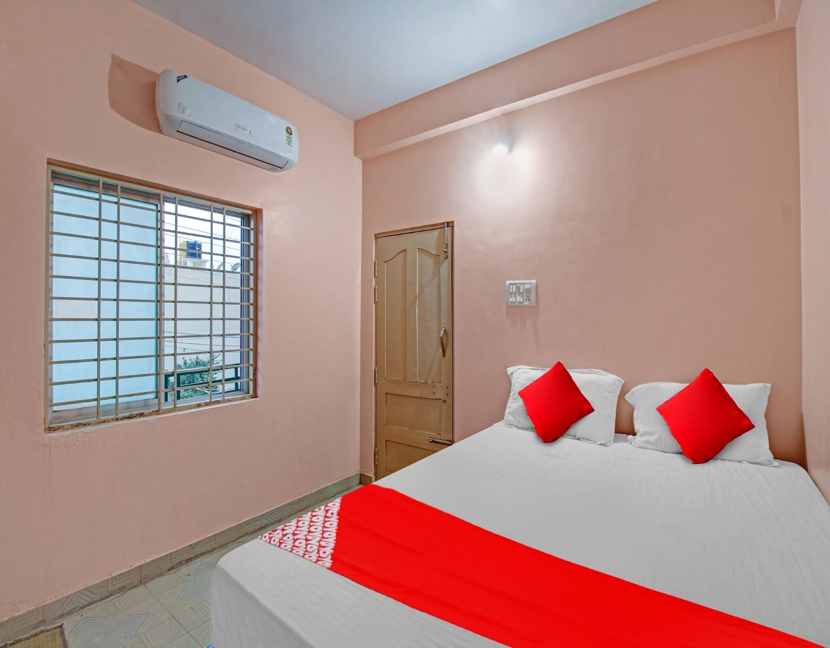 A bedroom with a bed, a window with bars, an air conditioning unit, and a door.
