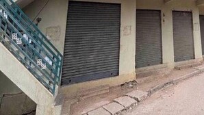 Filera d'edificis amb persianes tancades i una escala de formigó que porta a l'entrada.